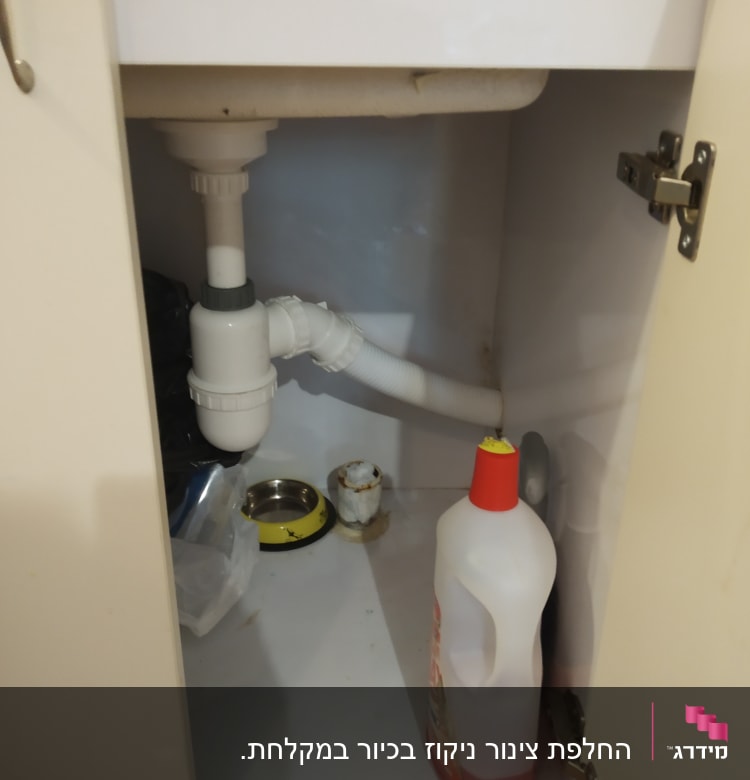 צנרת מתחת לכיור עם בקבוק חומר ניקוי